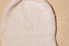 A white hat with a pink faux fur pom that I test-knit for a designer.