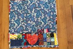 A sewing mat/organizer in blue paisley fabric with a variety of other fabrics used for the pockets.